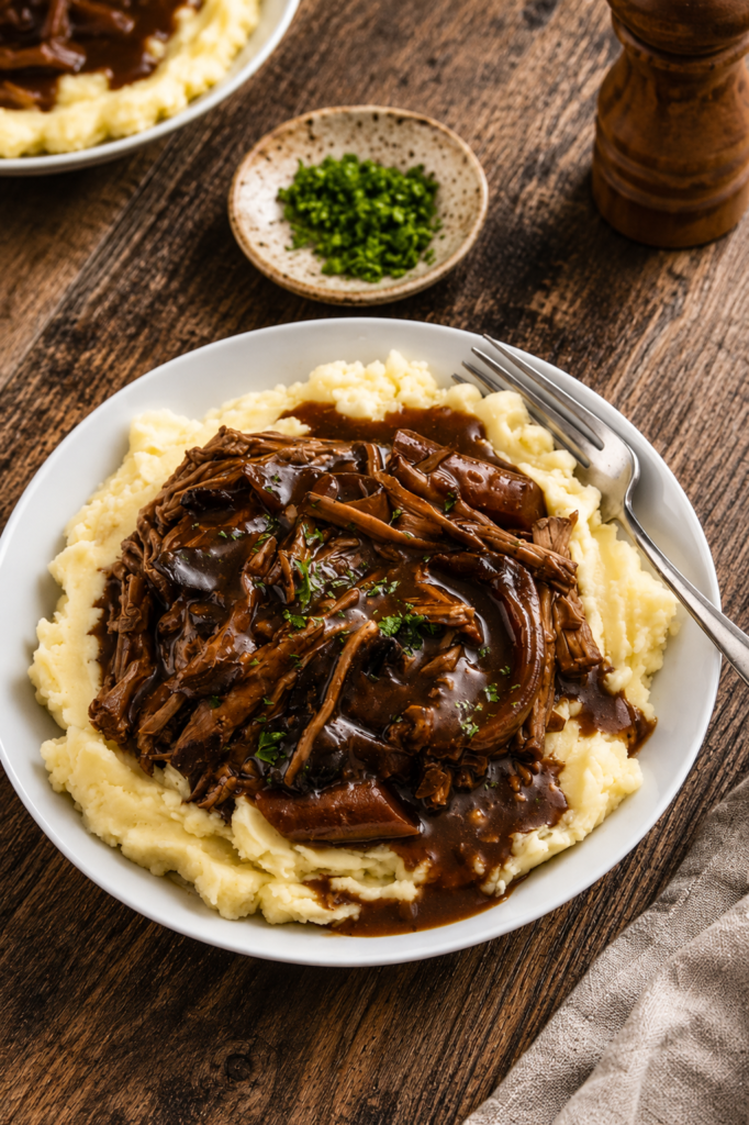 Shredded chuck roast served over garlic mashed potatoes with gravy