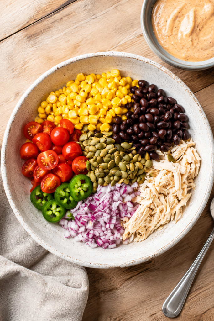Dressing being poured over southwest chicken salad