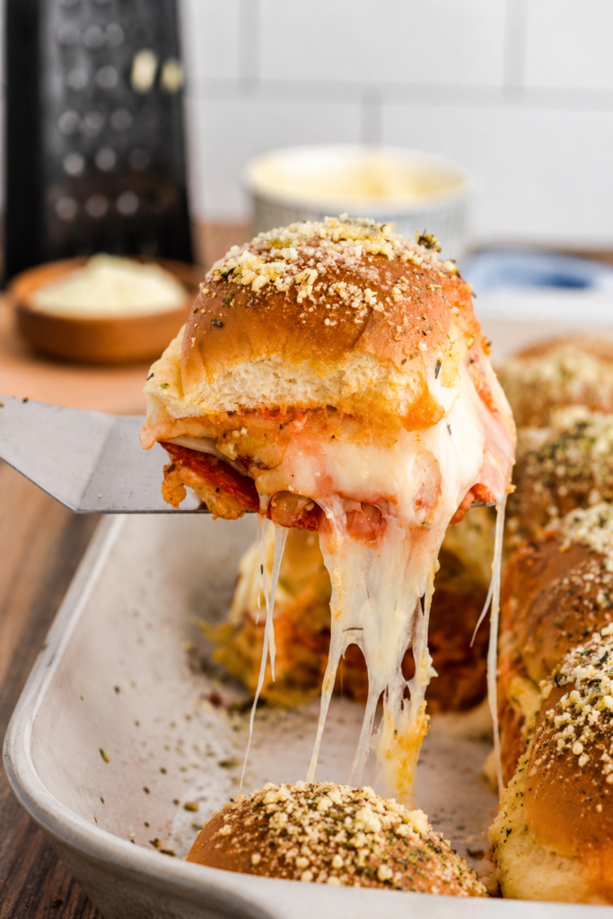 Pepperoni and cheese layered on slider rolls in a baking dish