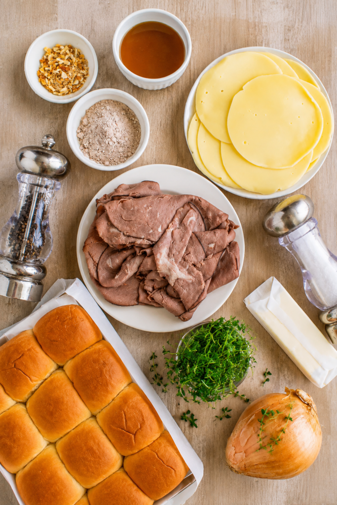 Roast beef layered on slider rolls in a baking dish