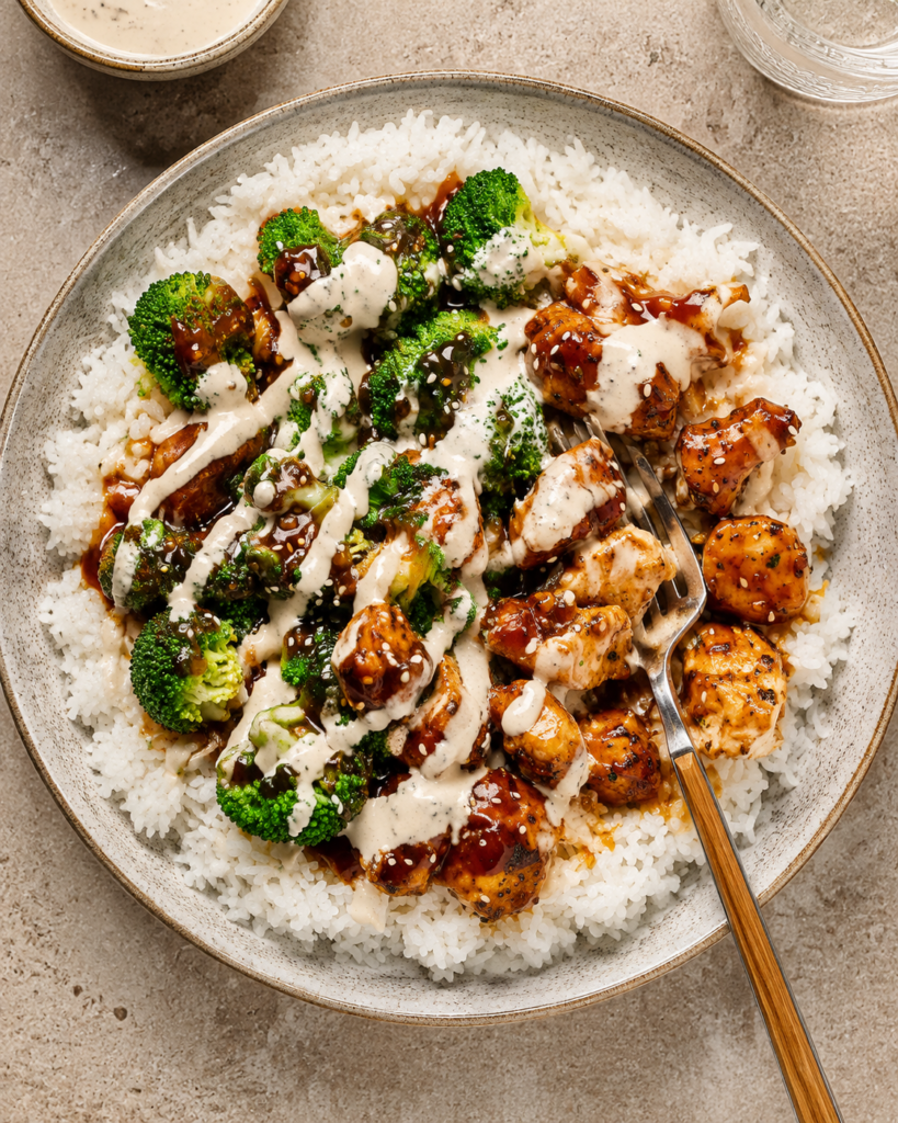 Sticky chicken served over rice with sesame seeds and green onions